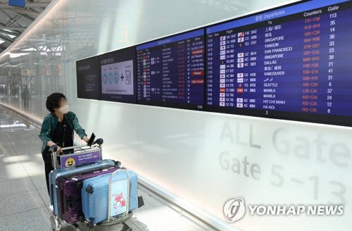 资料图片：一名旅客在仁川国际机场查看航班时刻表。 韩联社