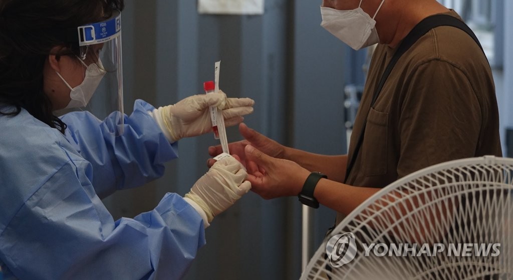资料图片：在一处新冠临时筛查诊所，市民为接受核酸检测做准备。 韩联社