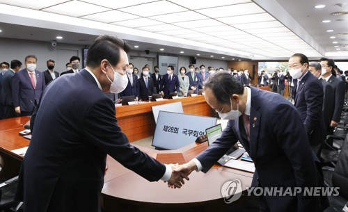 资料图片：6月21日，在首尔龙山总统办公室举行的国务会议上，尹锡悦（左）与秋庆镐握手致意。 韩联社