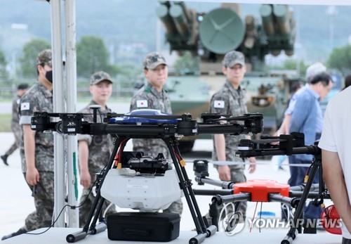 资料图片：6月24日，在京畿道杨州市，参访无人机机器人（Dronbot）庆典的军方有关人士走过无人机展台。 韩联社