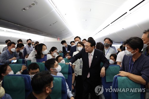 当地时间27日，在韩国“空军一号”总统专机上，尹锡悦（居中）与随行记者们攀谈。 韩联社