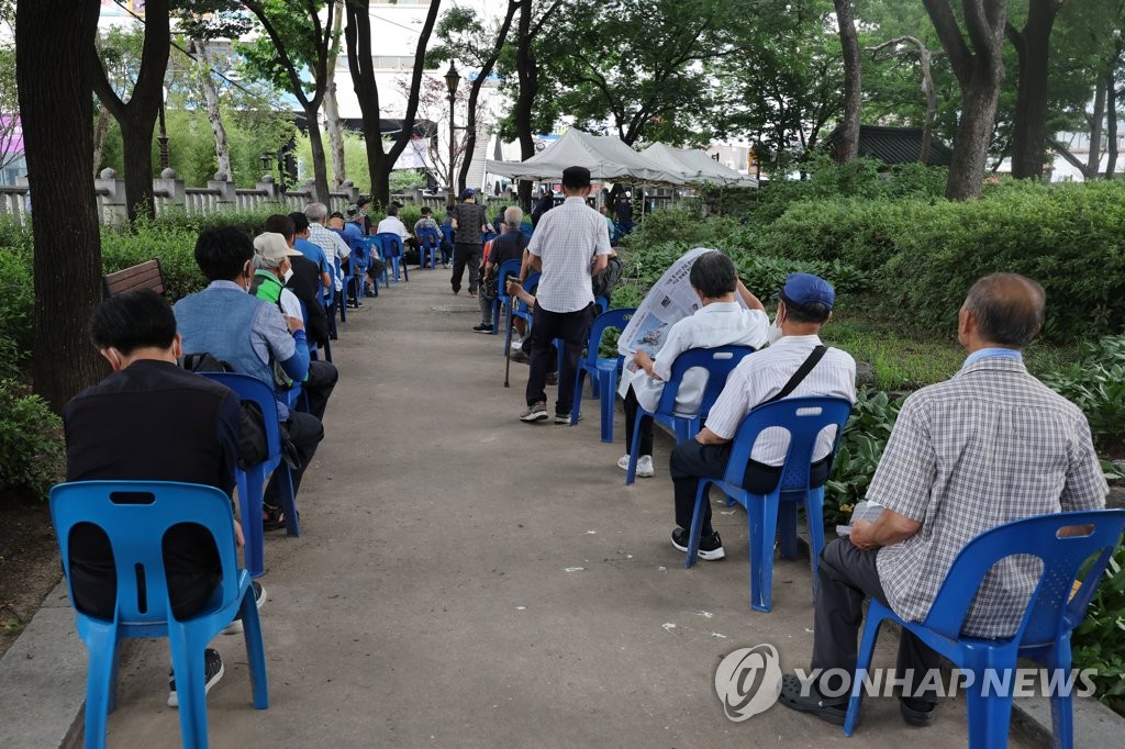 资料图片：7月4日，在首尔钟路区的塔谷公园附近，老人们排队等待免费供餐。 韩联社
