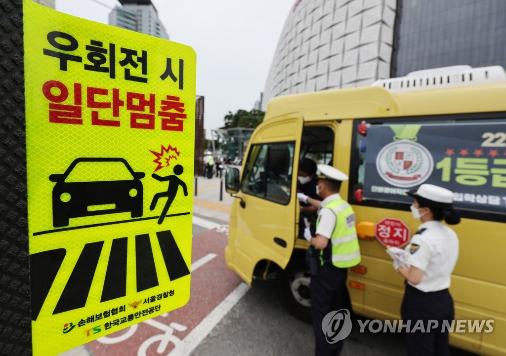 资料图片：7月12日，在首尔市松坡区的一处十字路口，交警正在引导车辆遵守“右转之前先停车”交规。新版《道路交通法》当天起正式施行，新法加强了司机的行人保护义务。 韩联社