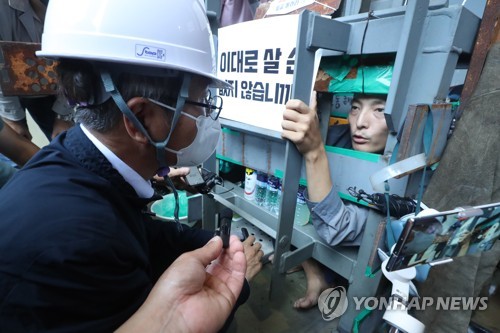 资料图片：7月19日，在庆尚南道巨济市的大宇造船海洋玉浦造船厂罢工现场，劳动部长官李正植（左）与示威人员交谈。 韩联社