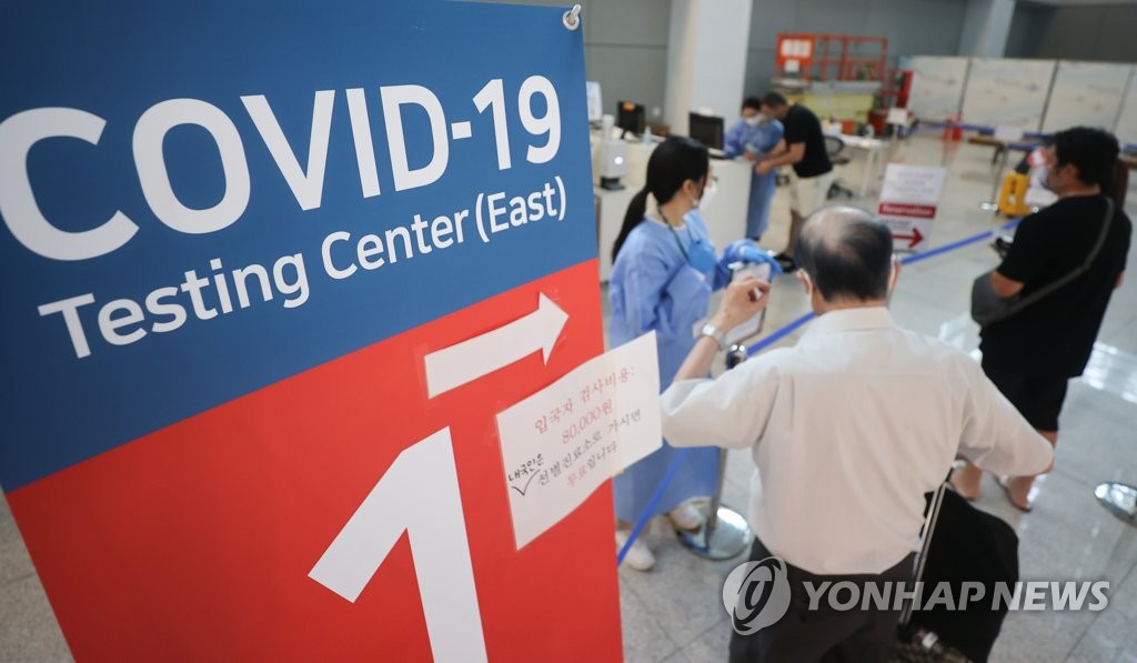 资料图片：7月24日，在设于仁川国际机场第二航站楼的新冠筛查诊所，医务人员指引入境人员接受新冠核酸检测。 韩联社