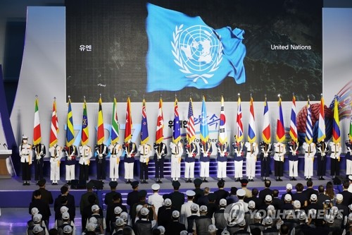 7月27日上午，韩国战争联合国军参战日纪念仪式在首尔东大门设计广场举行。图为旗手在台上举出22个联合国军参战国国旗和韩国国旗太极旗。 韩联社