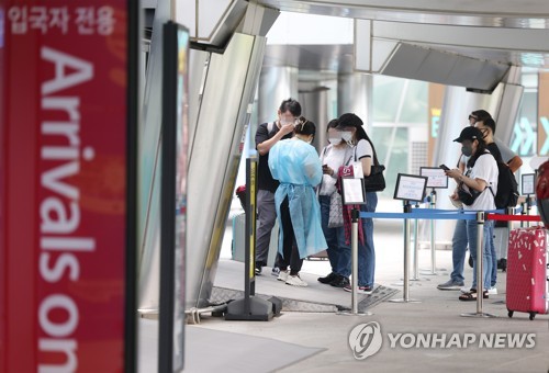 资料图片：外籍旅客前往机场新冠检测中心。 韩联社
