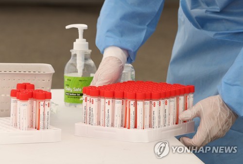资料图片：7月28日，在设于首尔站的临时筛查点，工作人员整理采样管。 韩联社