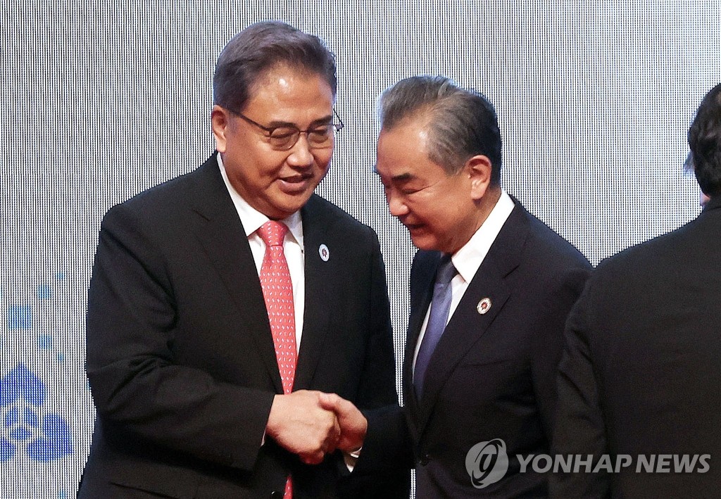 8月4日，在柬埔寨金边，朴振（左）和王毅在东盟与韩中日外长会上合影后握手寒暄。 韩联社