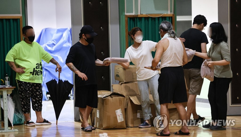 8月9日，在设于首尔市铜雀区一所小学的安置点，灾民正领取物资。 韩联社