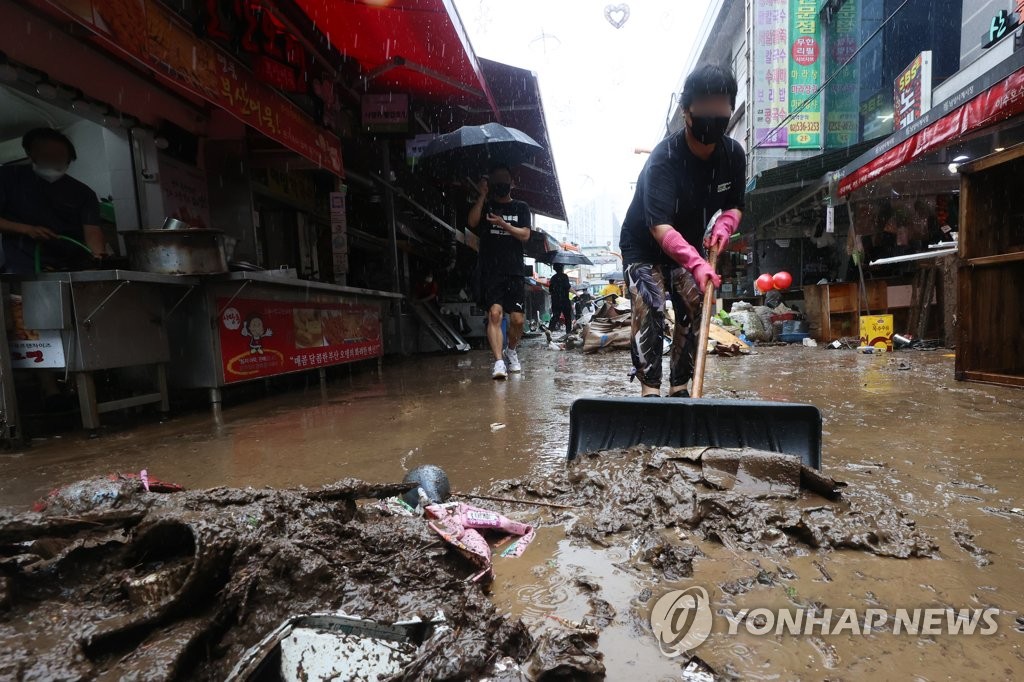 8月9日，在首尔铜雀区南城沙溪市场，一位商人在暴雨过后清扫积水和垃圾。 韩联社
