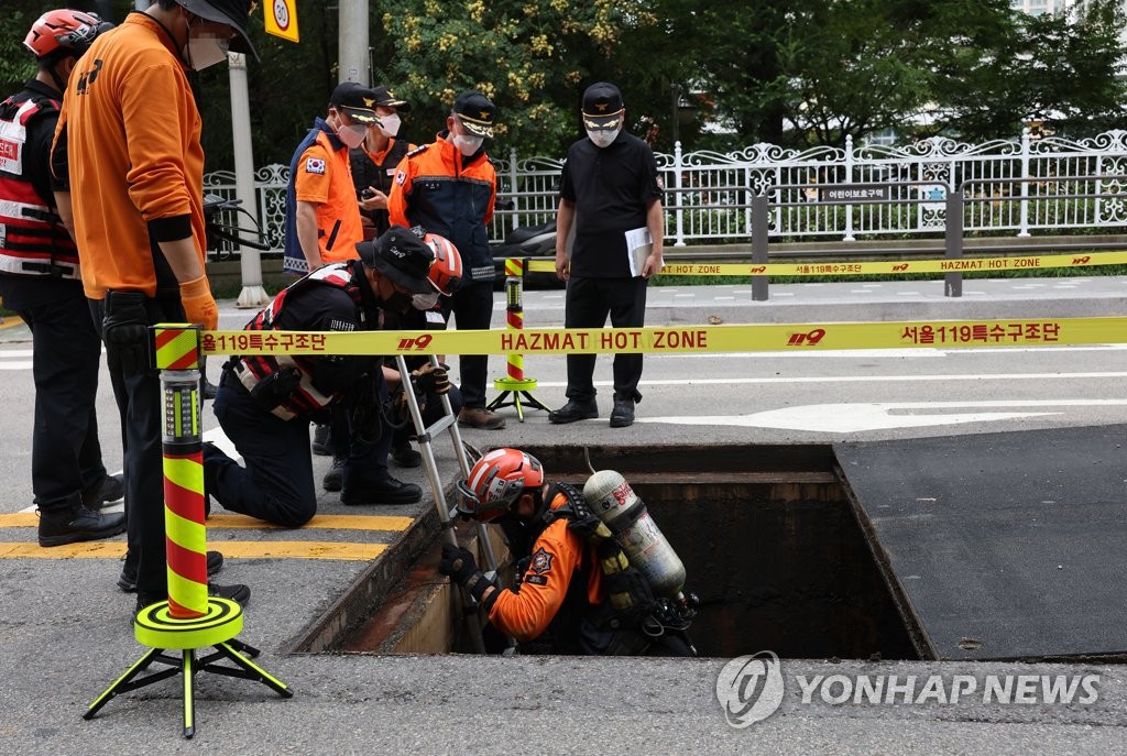 8月10日，在首尔江南地铁站附近，119救援人员正在搜寻暴雨中失踪的人员。 韩联社