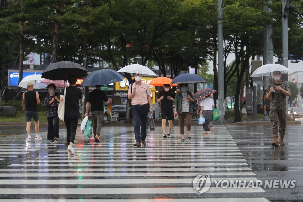 资料图片：8月11日下午，在光州市，市民雨天打伞出行。 韩联社