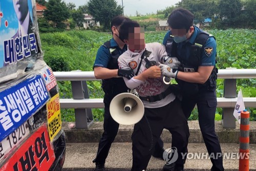 资料图片：8月16日，在庆尚南道梁山市平山村，警察以特殊威胁嫌疑逮捕了一名用刀威胁前总统文在寅秘书室人员等引发骚乱的示威者。 韩联社/平山村居民脸书截图（图片严禁转载复制）