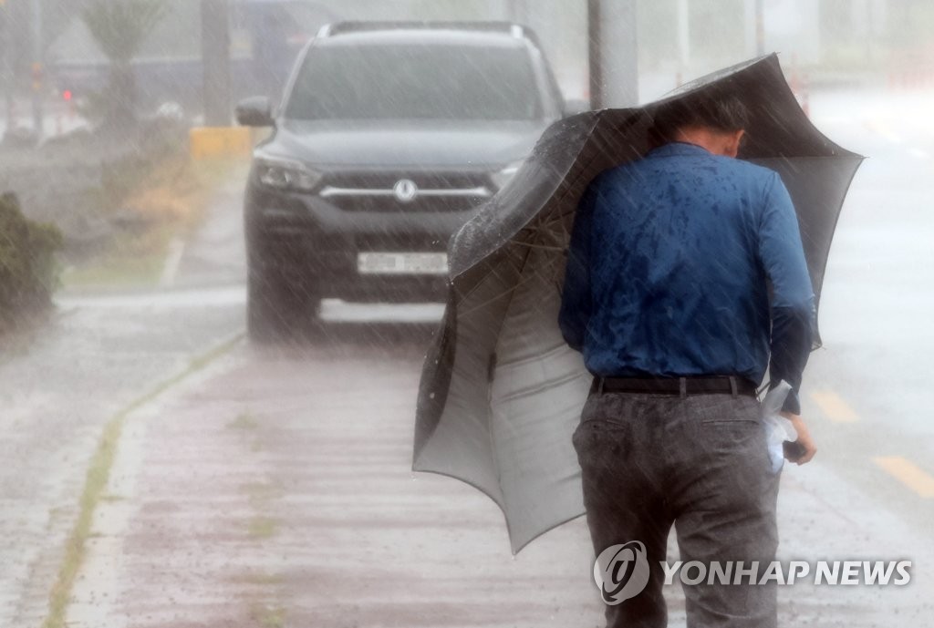 9月5日，在济州道西归浦市城山邑，一居民撑着雨伞顶风行走。 韩联社