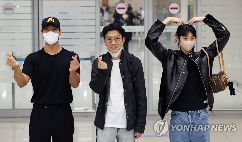 9月15日，在仁川国际机场，韩剧《鱿鱼游戏》主创人员下机后摆姿势供媒体拍照。左起依次是演员朴海秀、导演黄东赫、模特兼演员郑浩妍。 韩联社