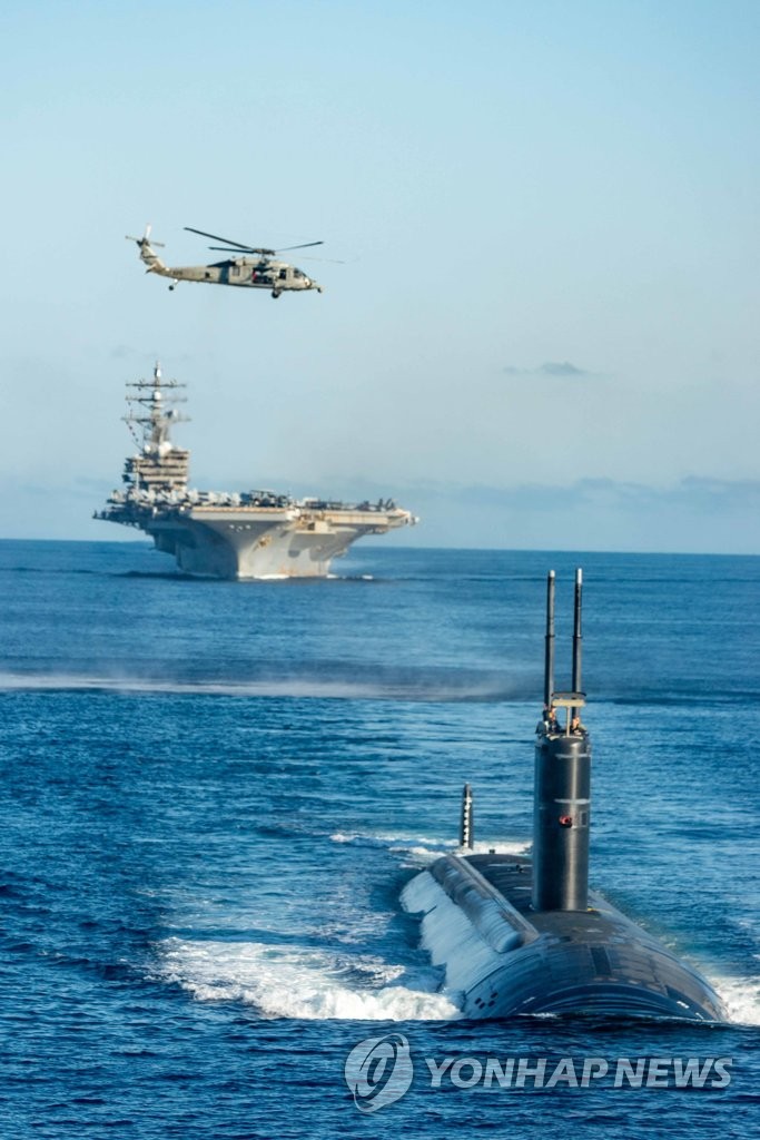 9月30日，在韩国东部海域，韩美日举行联合反潜演习。由下到上依次是参演的美军“安纳波利斯”号潜艇、“里根”号核航母、MH-60“海鹰”反潜直升机。 韩联社/韩国海军供图（图片严禁转载复制）