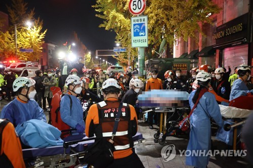 10月29日夜间，在首尔市龙山区梨泰院洞踩踏事故现场，救援人员正在护送伤员。 韩联社