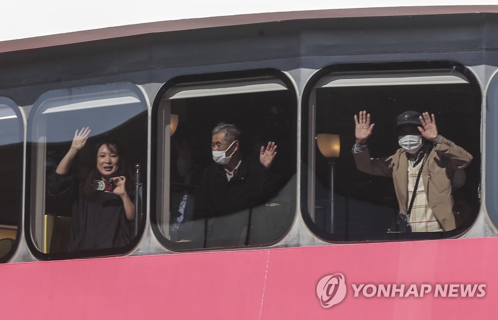 11月4日，在釜山港的国际客轮码头，搭乘“甲虫女王”号客轮的游客们向记者挥手致意。 韩联社