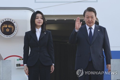 11月11日，在位于京畿道城南市的首尔机场，韩国总统尹锡悦（右）和夫人金建希站在专机舷梯上向送行人群致意。 韩联社