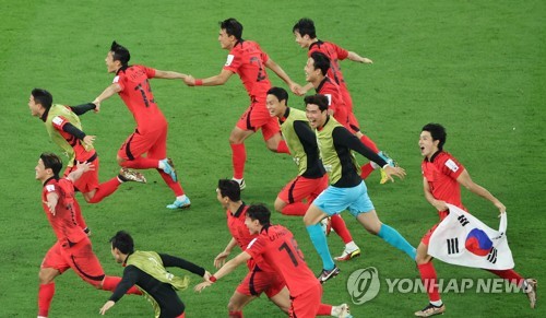 韩国时间12月3日凌晨，在卡塔尔赖扬教育城体育场进行的2022年卡塔尔世界杯H组第三轮比赛中，韩国队击败葡萄牙队成功晋级16强。图为韩国代表队举国旗庆祝晋级。 韩联社