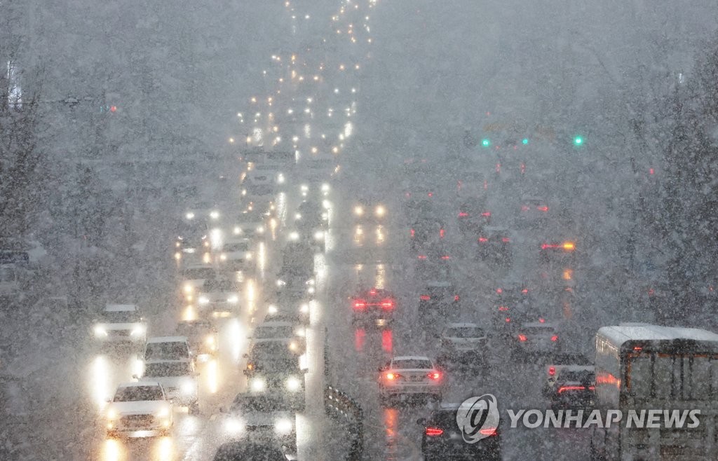 资料图片：12月13日，在京畿道水原市八达区一带下起大雪，汽车减速慢行。 韩联社