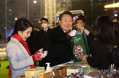 资料图片：12月16日，在首尔钟路区“开放松岘广场”，韩国总统尹锡悦夫妇出席冬季购物节“Win·Winter Festival”并选购物品。 韩联社