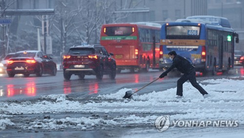 资料图片：2022年12月21日，在首尔光化门一带，工作人员正进行除雪作业。 韩联社
