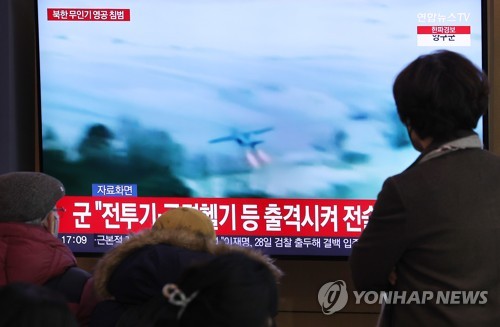资料图片：12月26日，在首尔火车站候车室，市民们收看朝鲜无人机入侵的新闻。 韩联社