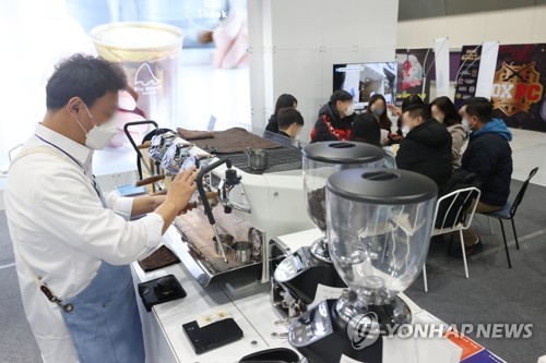 资料图片：1月5日，“第68届特许经营店创业博览会”在首尔江南区的韩国国际会展中心（COEX）举行。图为一家参展商的工作人员正在制作咖啡。 韩联社