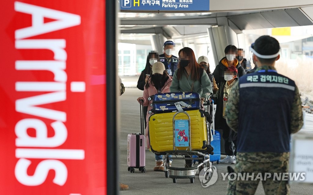 资料图片：1月8日，在仁川国际机场第一航站楼，自华入韩旅客在防疫人员的指引下走向新冠筛查中心。 韩联社