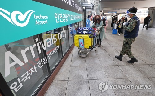 资料图片：1月8日下午，在仁川国际机场第一航站楼，来自中国的入境人员在工作人员的指引下前往核酸检测中心。 韩联社