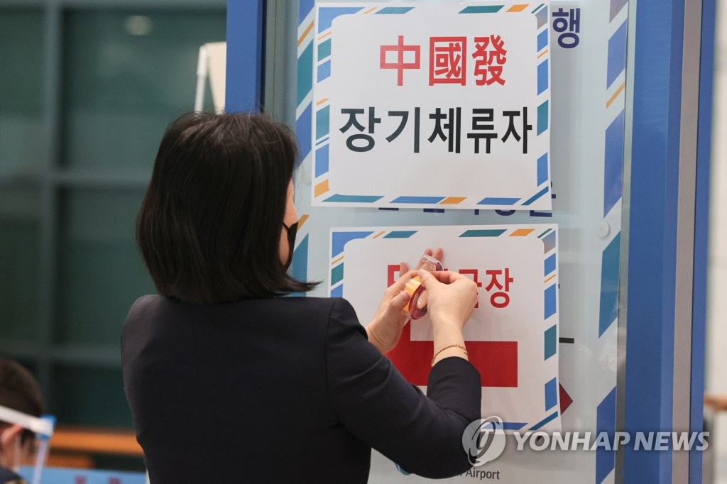 资料图片：1月9日，在仁川国际机场，工作人员正在张贴自华入境人员指引牌。 韩联社