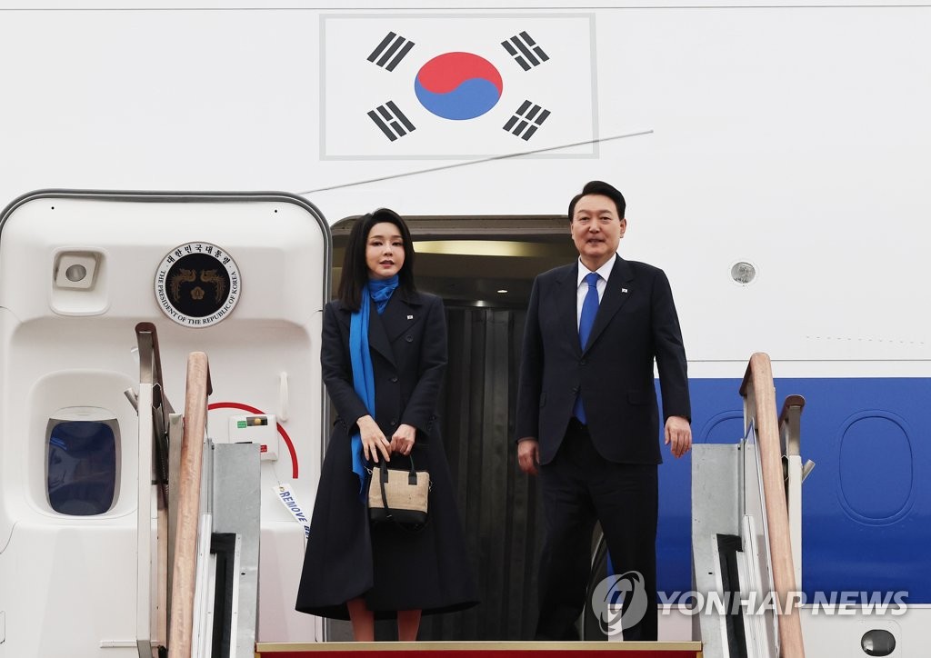 1月14日，在位于京畿道城南市的首尔机场，韩国总统尹锡悦（右）和夫人金建希在总统专机舷梯上向送行人群致意。尹锡悦当天开启为期八天的非欧之旅，先后访问阿联酋和瑞士。 韩联社
