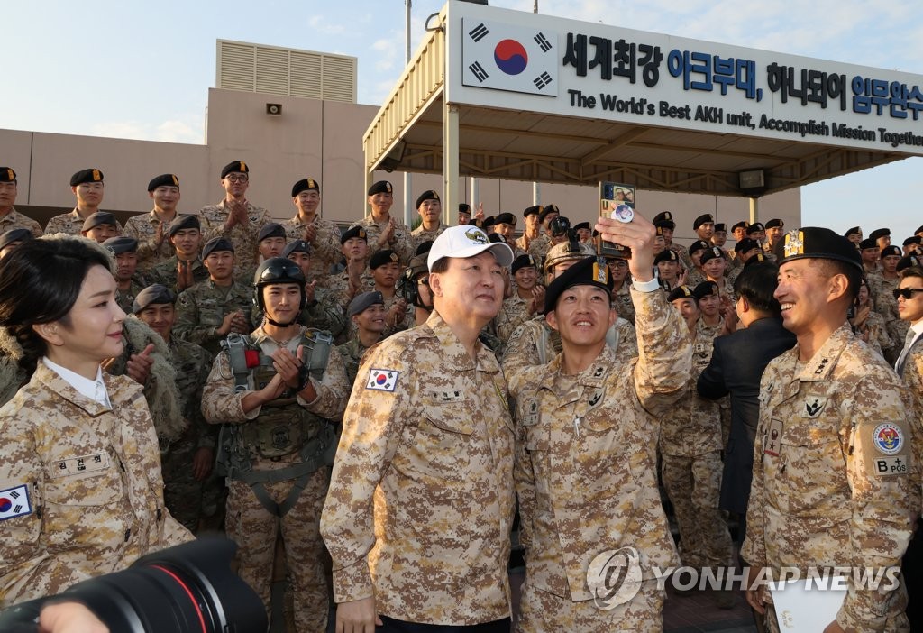 当地时间1月15日，韩国总统尹锡悦访问驻扎在阿联酋的兄弟部队看望慰问官兵。图为尹锡悦（戴白帽子）与官兵们拍照留念。 韩联社
