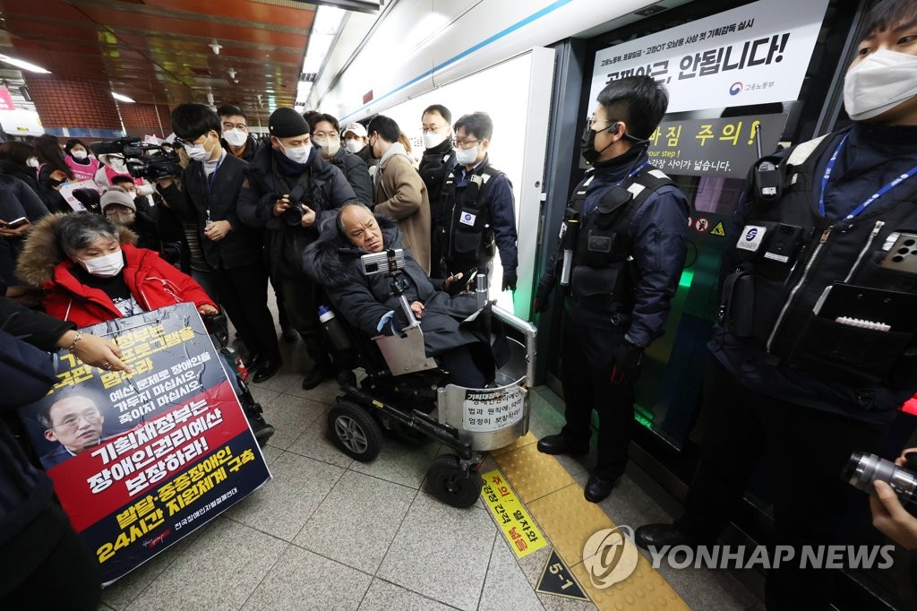 1月20日，在首尔地铁四号线首尔站，全国残疾人反歧视联盟成员试图上车，遭人墙堵截。 韩联社
