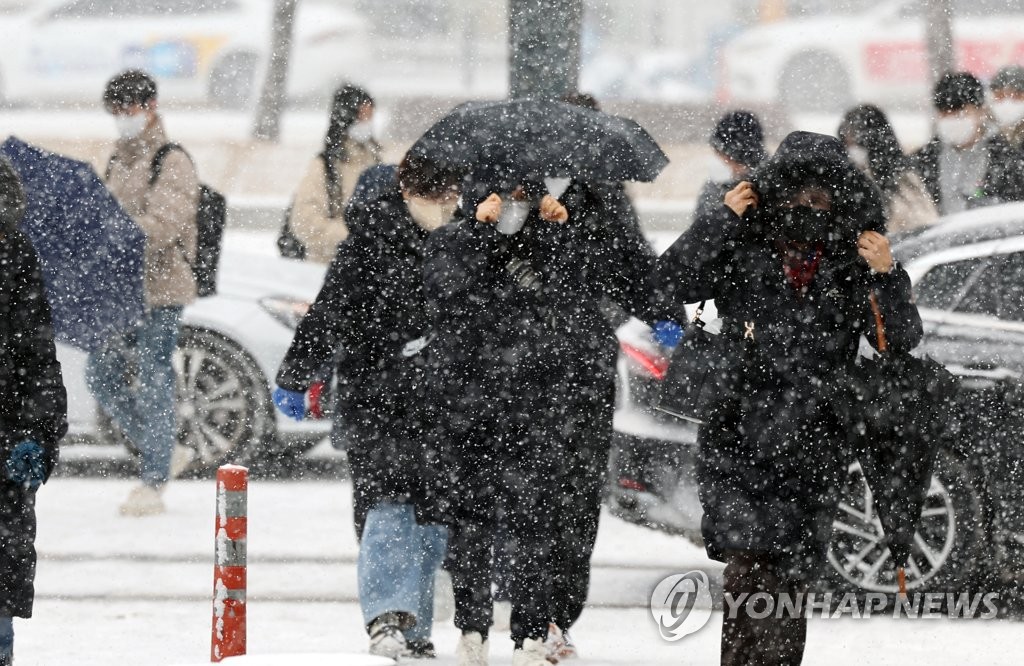 资料图片：市民们在纷飞的雪花中出行。 韩联社