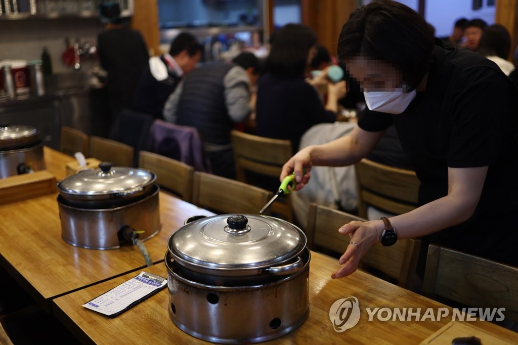 资料图片：1月27日，在首尔的一家餐厅，服务人员正在给煤气灶点火。 韩联社
