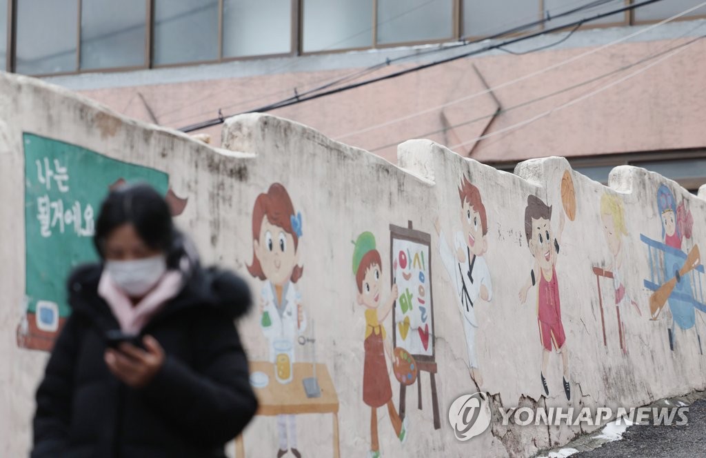 资料图片：1月29日，在首尔城东区，一位市民戴着口罩出行。 韩联社