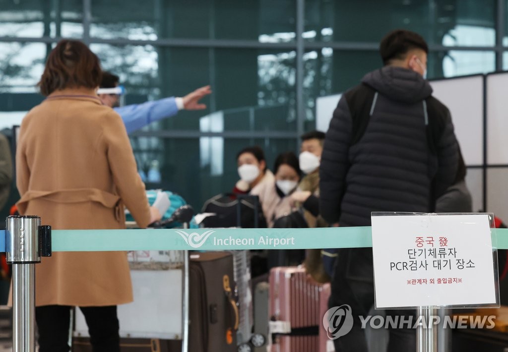 资料图片：2月12日，在仁川国际机场第一航站楼，自华入韩旅客接受防疫人员的指引。 韩联社