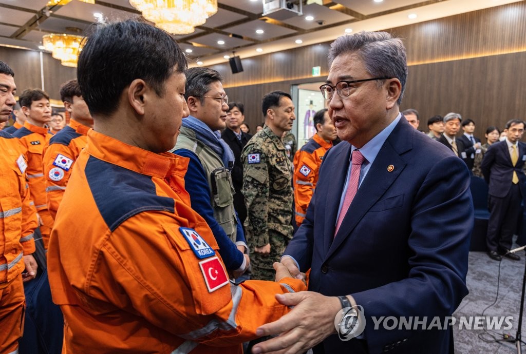 2月23日，在外交部大楼，韩国外交部长官朴振（右）邀请韩国紧急救援队（KDRT）第一批队员举行座谈会。图为朴振与救援队员握手。 韩联社