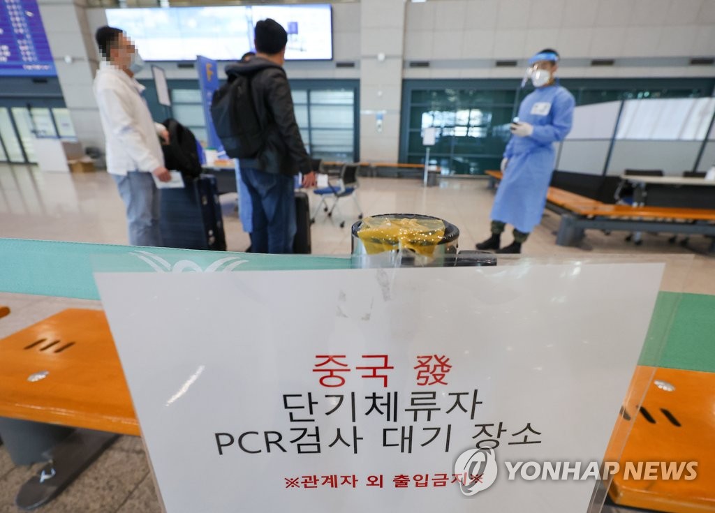 资料图片：2月27日，在仁川国际机场第一航站楼入境大厅，来自中国的旅客接受防疫工作人员的指引。 韩联社
