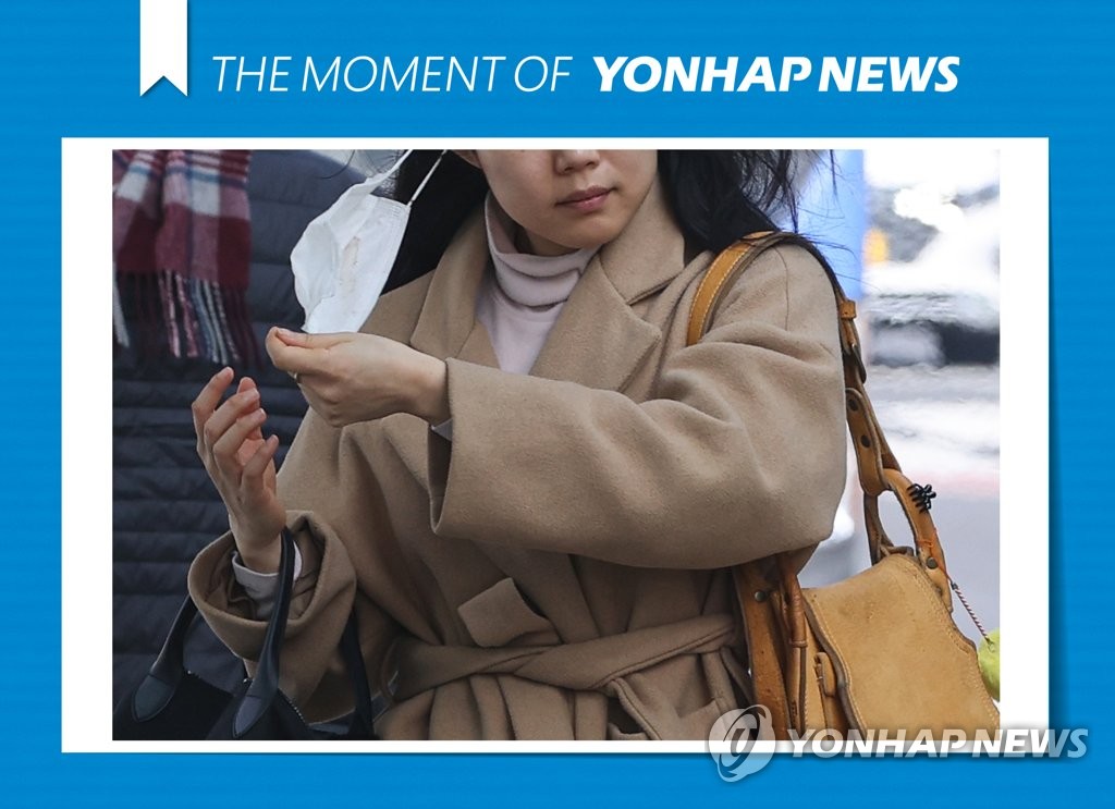 资料图片：3月5日，在首尔光化门广场公交车站，一位市民下车时摘下口罩。 韩联社
