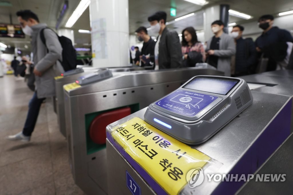 资料图片：3月15日，在首尔光化门地铁站，乘客们戴着口罩进站。 韩联社
