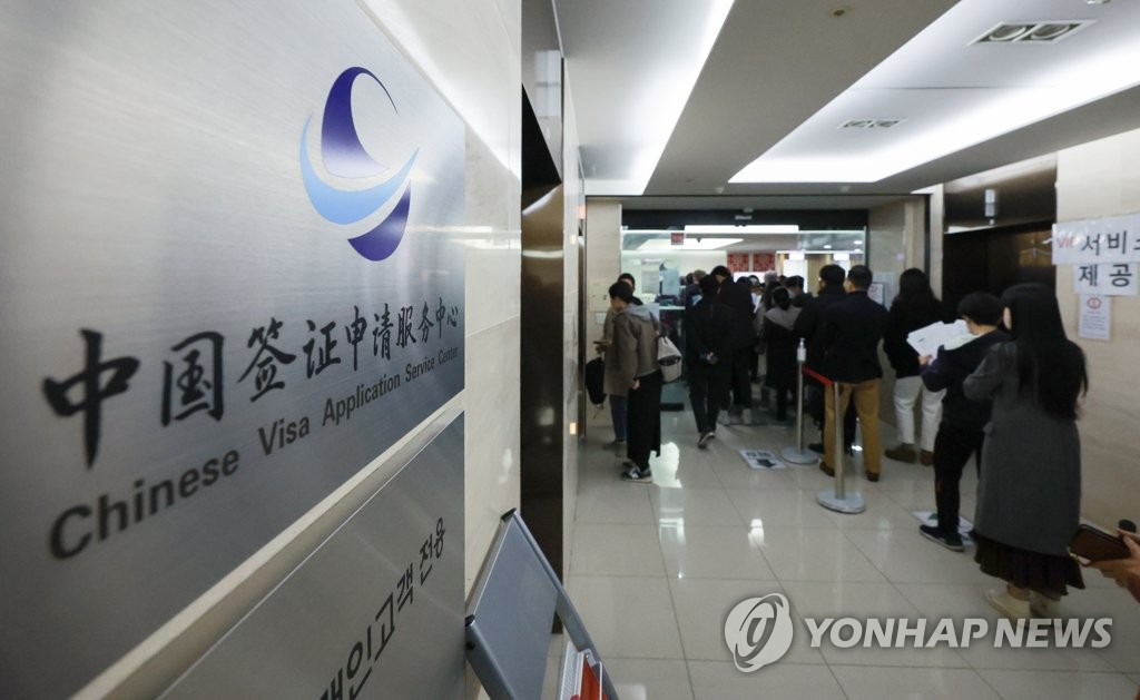 资料图片：3月15日，在首尔市一中国签证申请服务中心，不少人排队办理中国签证。 韩联社 