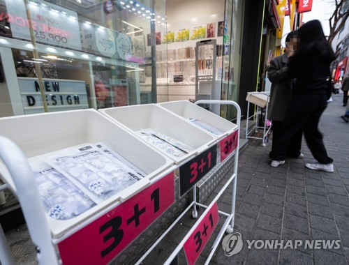 资料图片：3月15日，在首尔明洞，一家口罩店贴出买三赠一促销活动海报。 韩联社