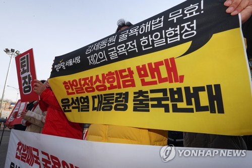 资料图片：3月16日，在京畿道城南市的首尔机场前，绿色党、正义党、进步党党员，以及反对尹锡悦政权的组织成员等手举标牌反对韩日首脑会谈。 韩联社