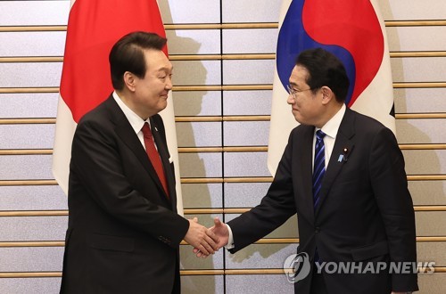 资料图片：3月16日，在位于东京的日本首相官邸，韩国总统尹锡悦（左）同日本首相岸田文雄举行首脑会谈。图为两位领导人在扩大会谈前握手合影。 韩联社