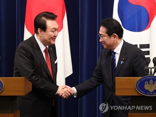 资料图片：3月16日下午，在日本东京的首相官邸，韩国总统尹锡悦（左）和日本首相岸田文雄举行会谈。图为两位领导人在结束联合记者会后握手致意。 韩联社