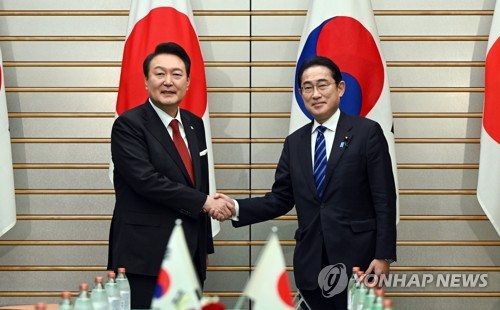 3月16日，在位于东京的日本首相官邸，韩国总统尹锡悦（左）同日本首相岸田文雄举行首脑会谈。图为两位领导人在扩大会谈前握手合影。 韩联社